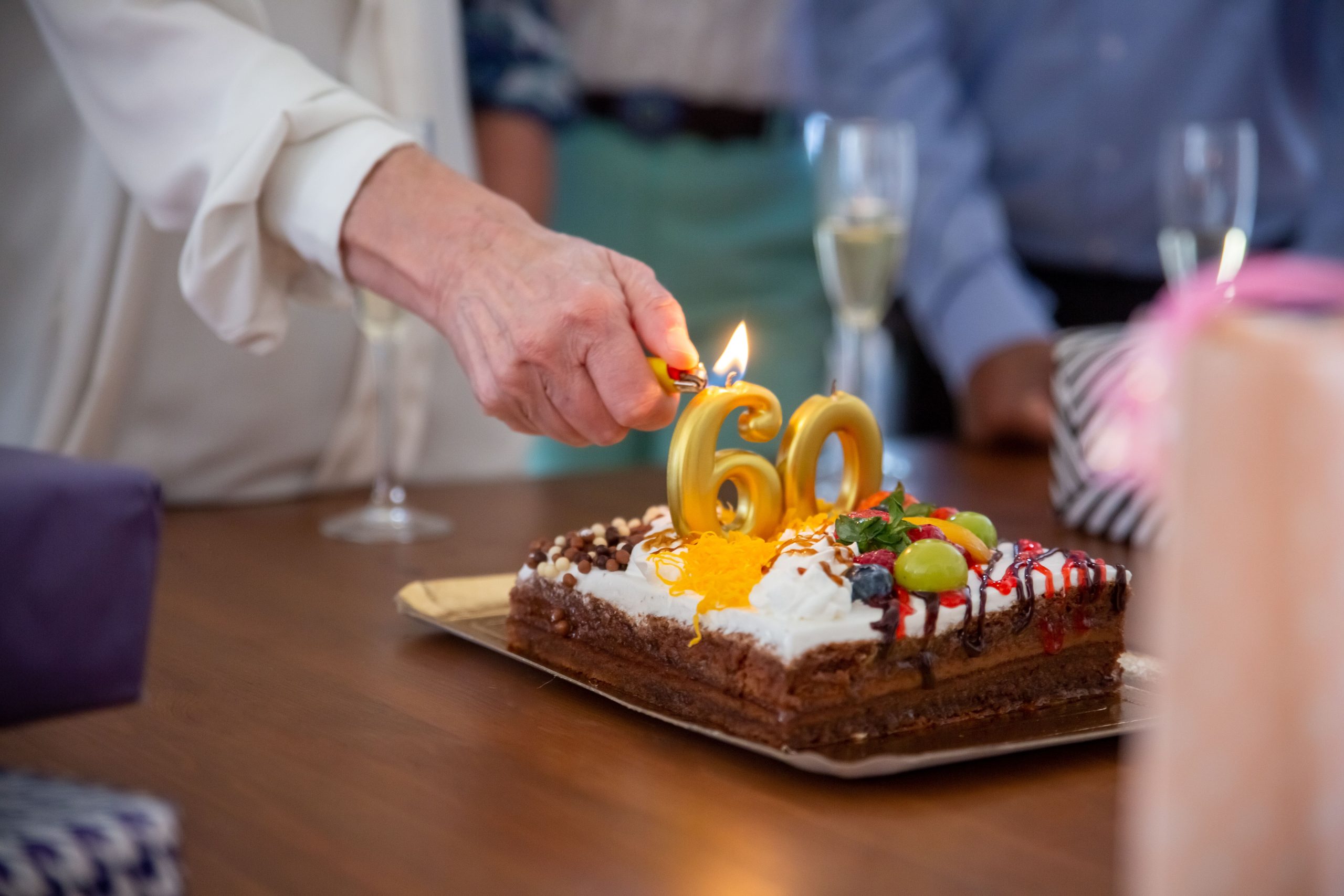 Main allumant bougies gâteau anniversaire numéro 60