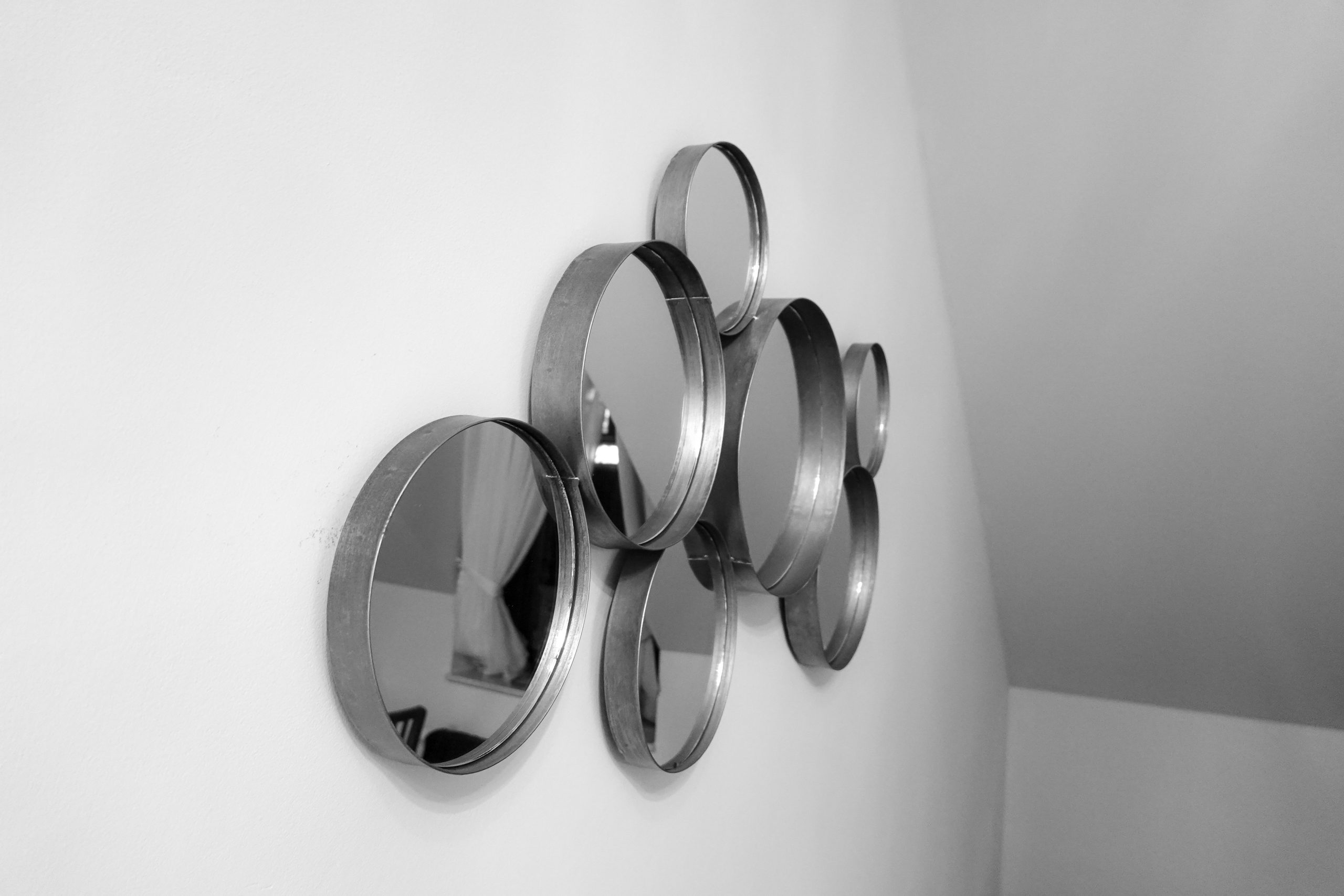 Collection miroirs ronds sur mur blanc.
