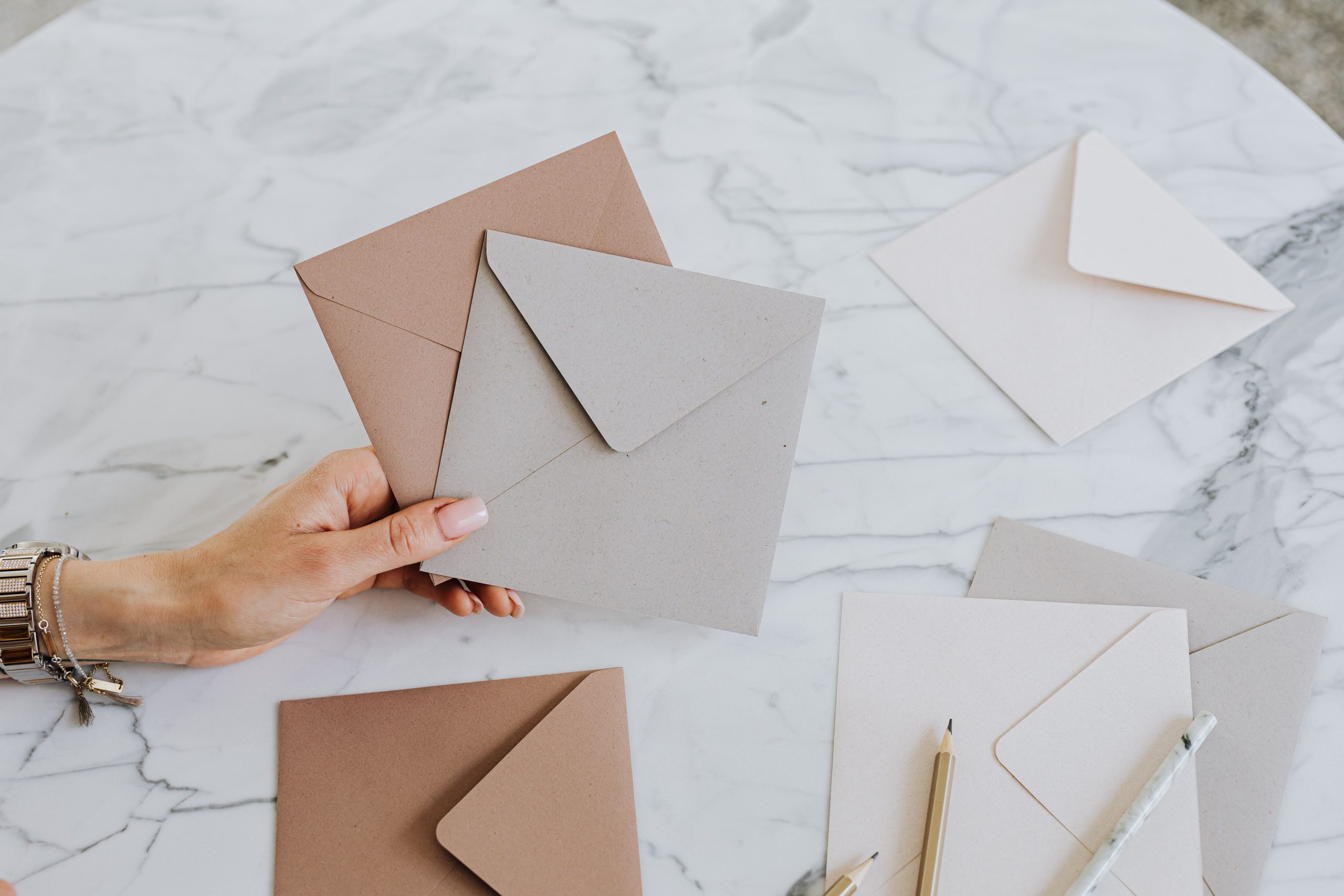 Main tenant enveloppes kraft sur table marbre