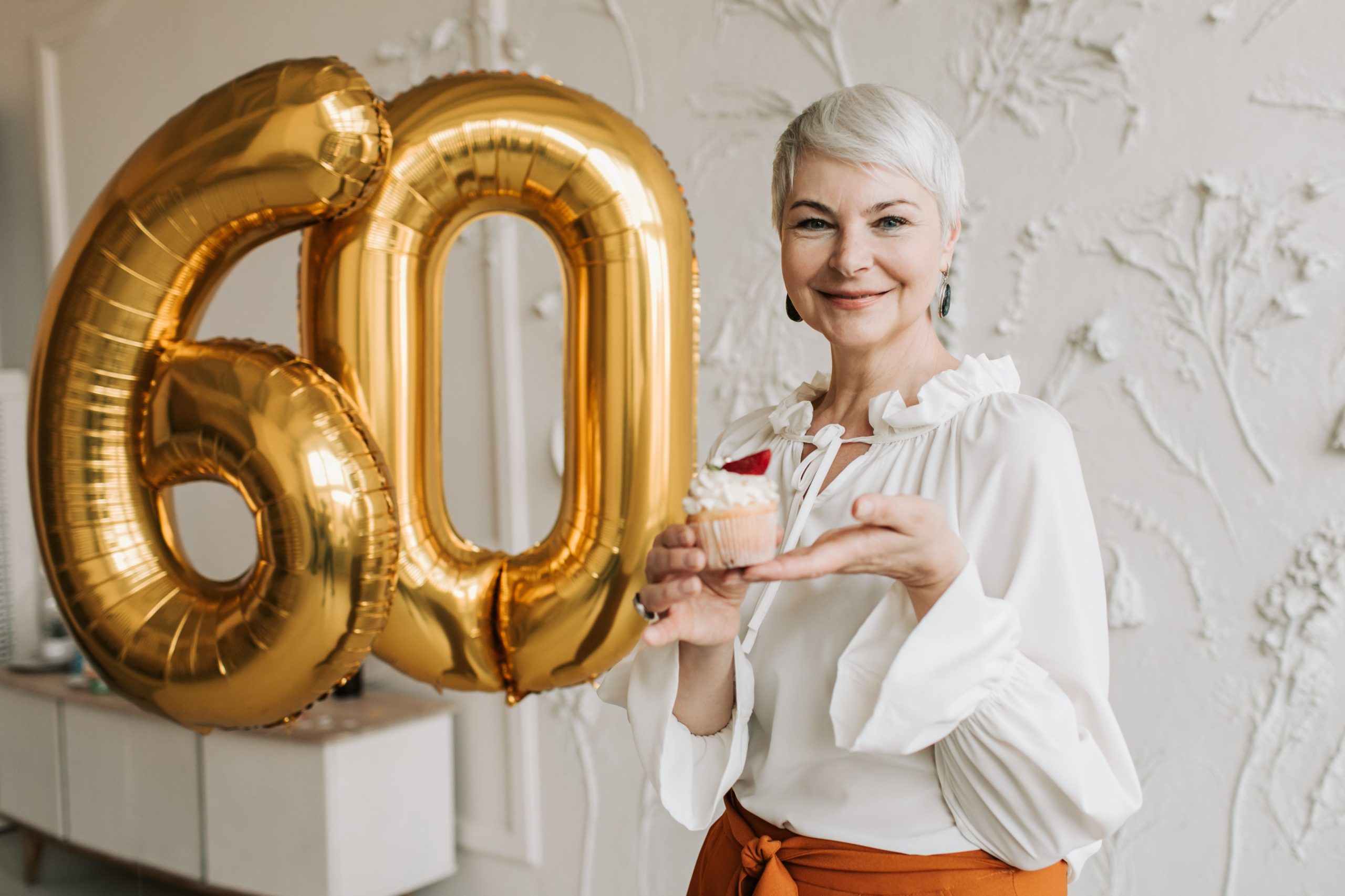 Femme senior cheveux gris tenant cupcake ballon 60