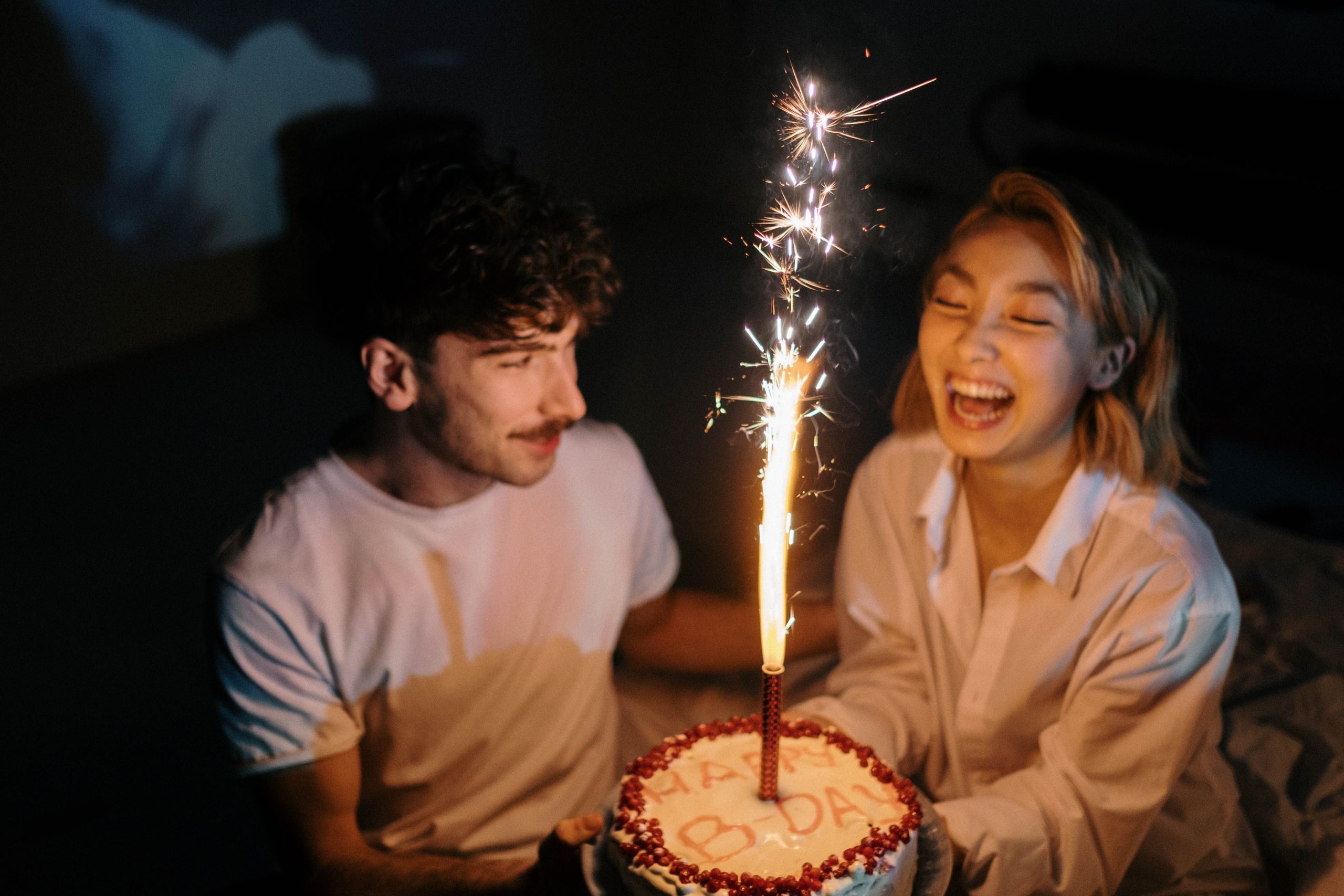 Couple riant devant gâteau anniversaire avec bougie