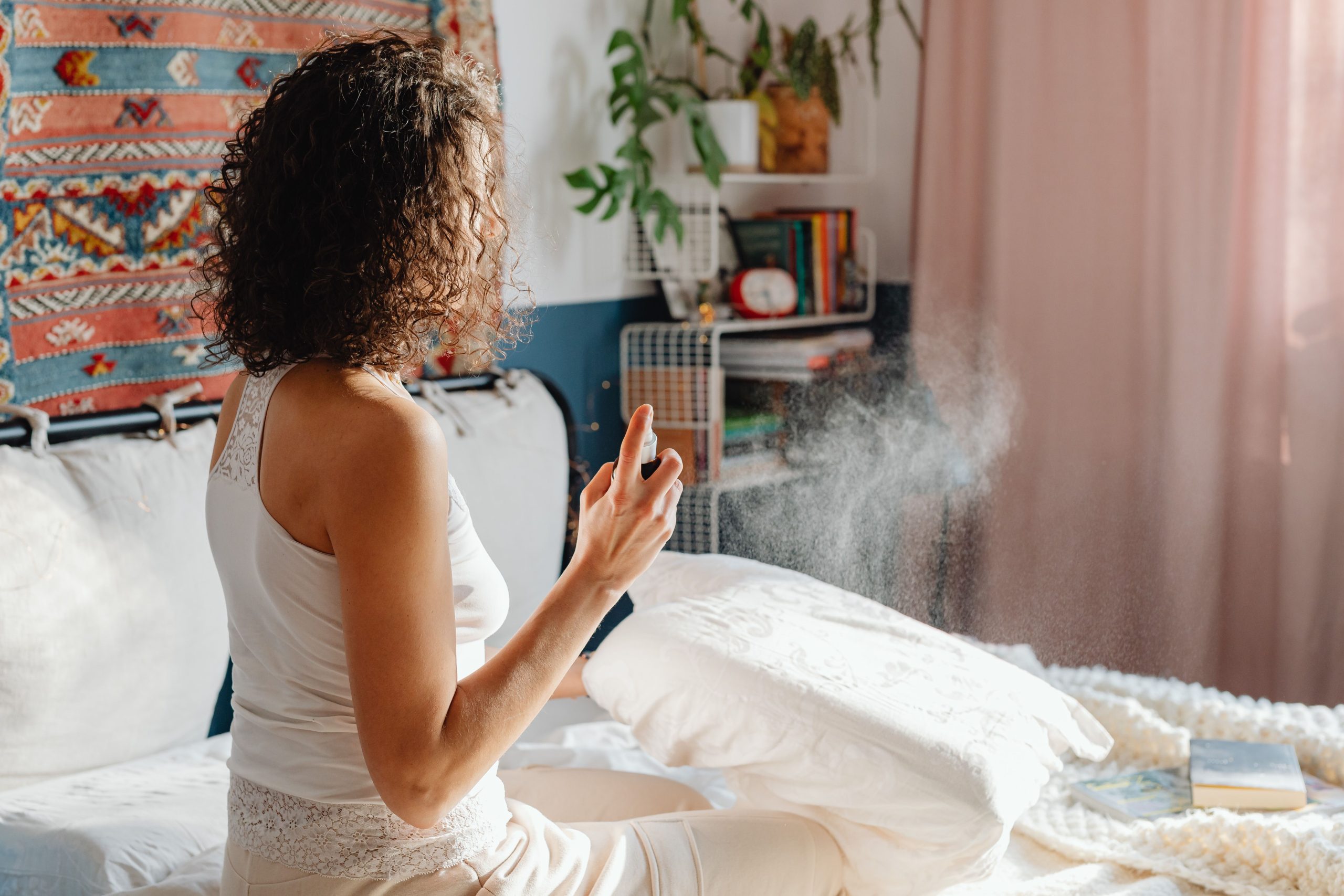 Femme vaporisant un brume parfumée dans sa chambre