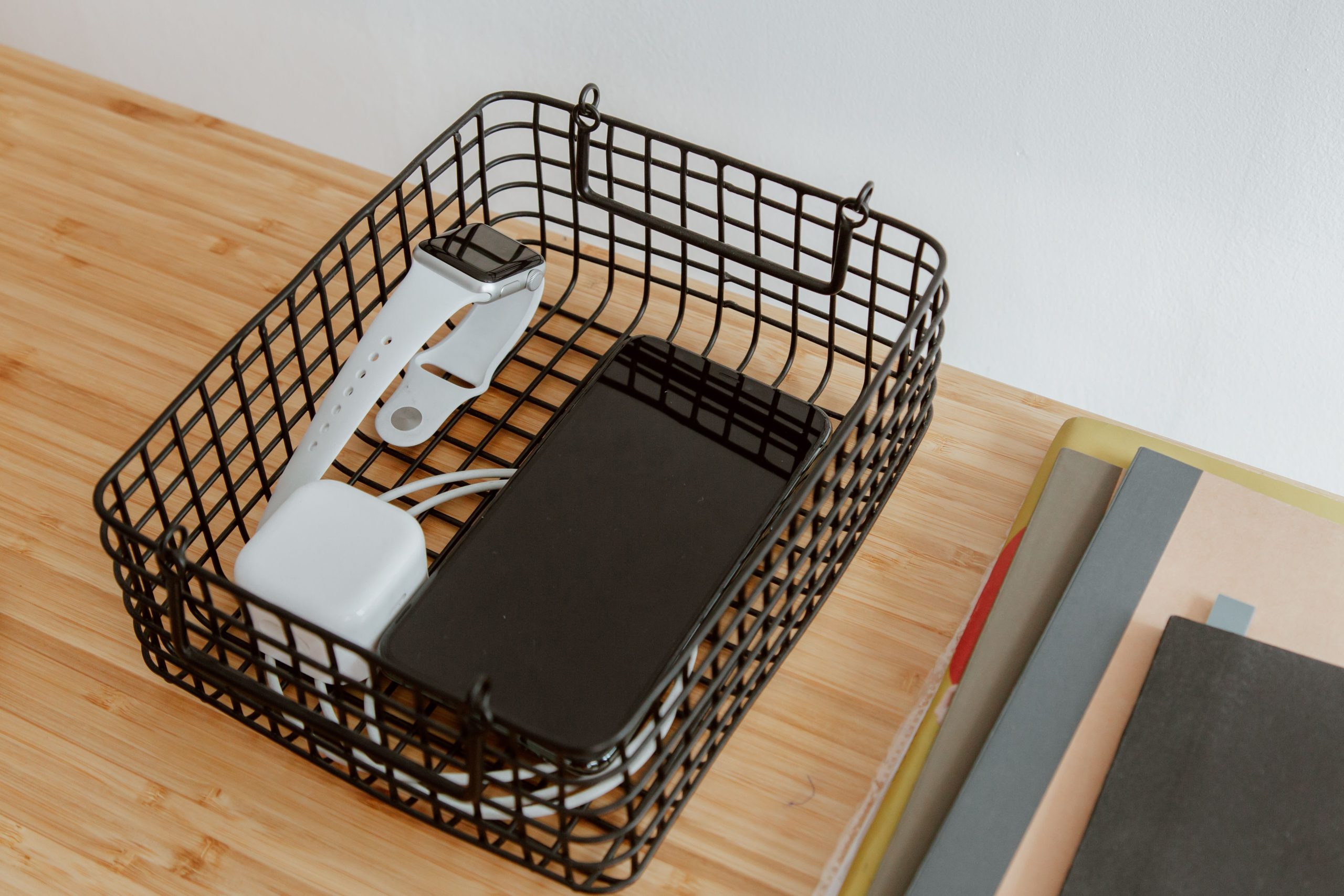 Panier métallique organisant gadgets sur bureau en bois
