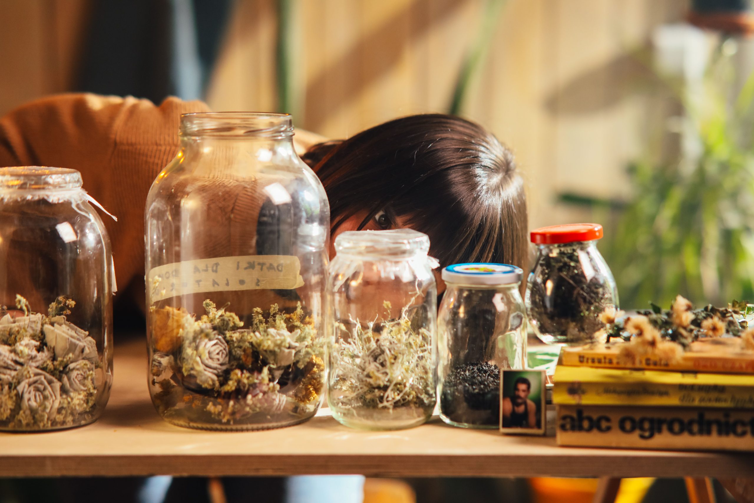 Femme observant des bocaux de fleurs séchées sur table